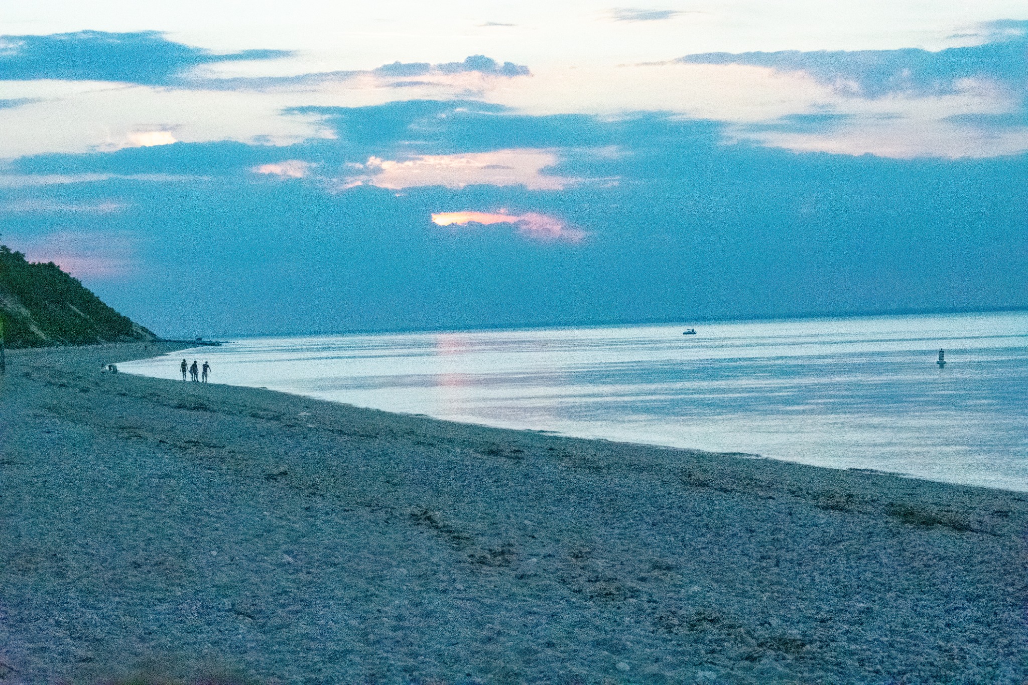 People walking along a beach at dusk