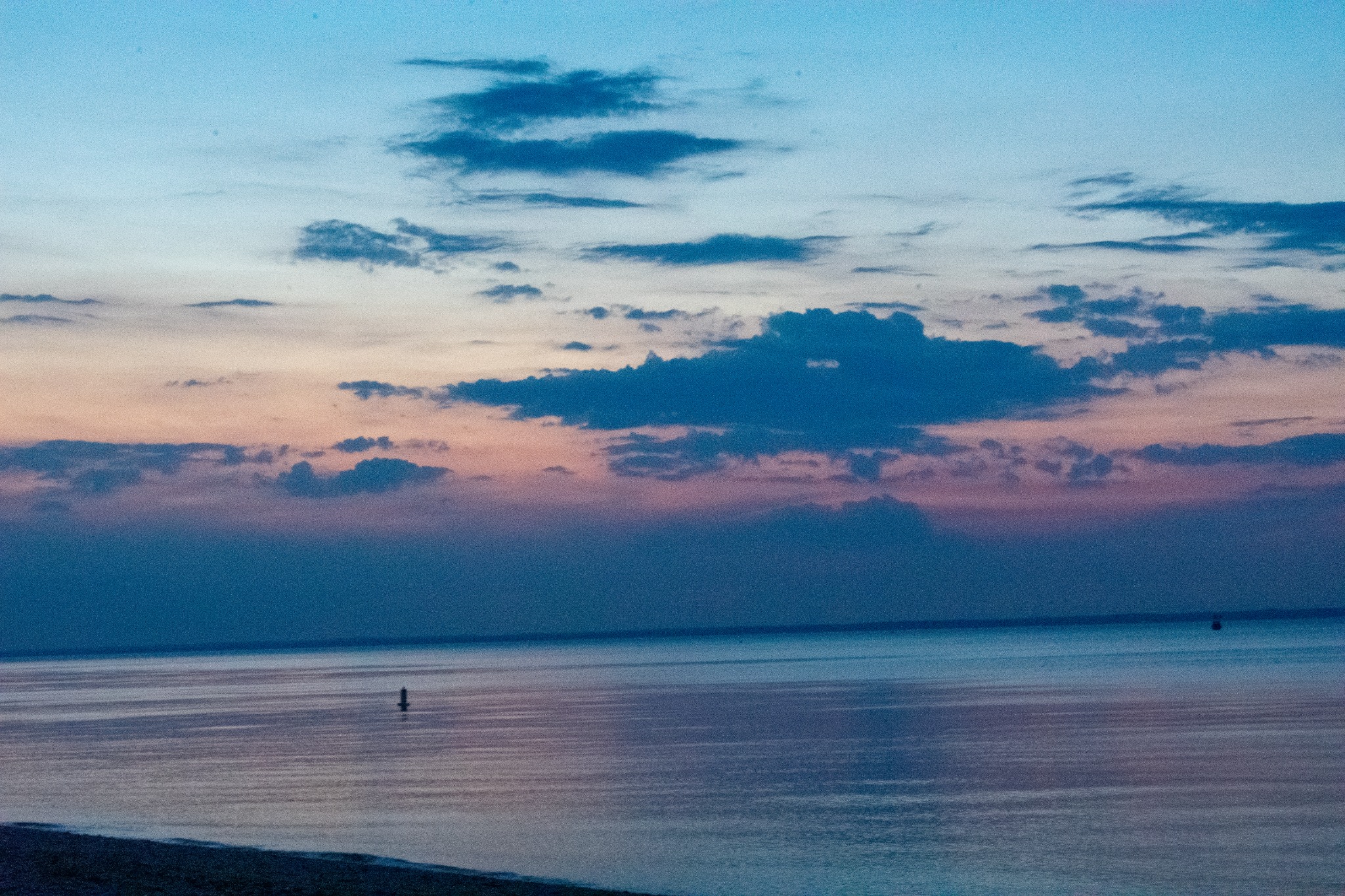 Blue hour over calm water with soft pink clouds