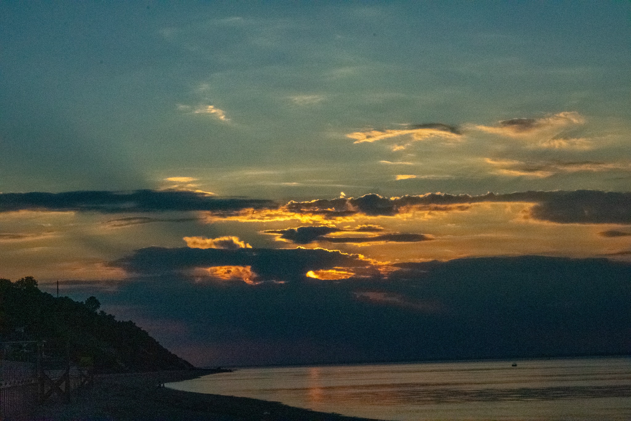 Golden sunset breaking through clouds over the water